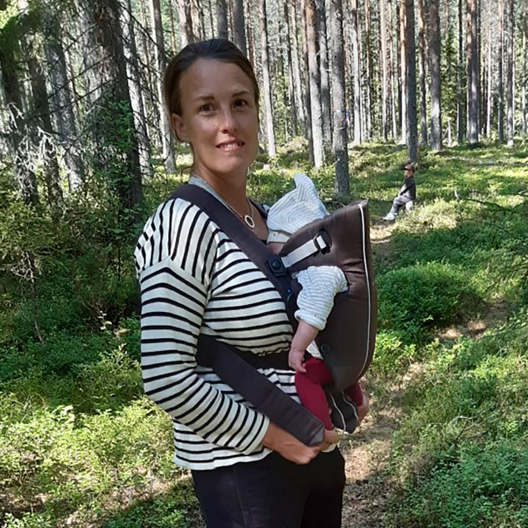 Mamma med barn i bärsele i skogen